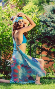 Yeşil çimlerin ve ormanın arka planında mayo giymiş manken görünümlü bir kız..