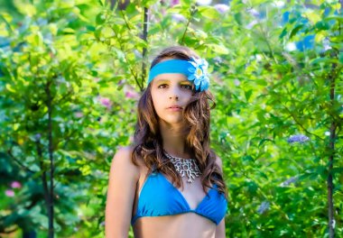 Yeşil çim ve ormanın arka planında mayo giymiş manken görünümlü bir kız. Boşluğu kopyala