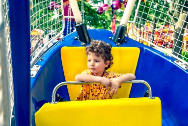 Atlıkarıncaya binen kıvırcık çocuk. Eğlence ve eğlence..