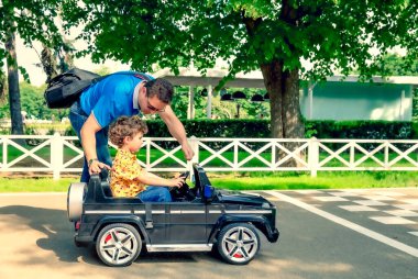 Baba ve oğlu lunaparkta. Baba oğluna güneşli bir yaz gününde araba sürmeyi öğretiyor. Başlangıç konseptinde ebeveyn yardımı.