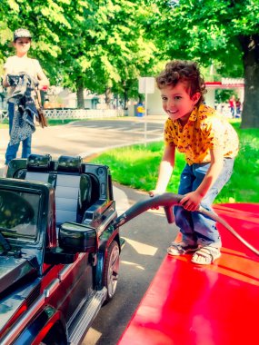 Lunapark, havalı çocuk benzin istasyonunda oyuncak araba çalıştırıyor.