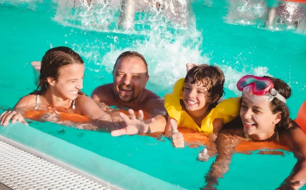 Cheerful family in swimming pool smiling at camera