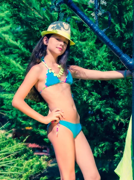 Yeşil çimlerin ve ormanın arka planında mayo giymiş manken görünümlü bir kız..