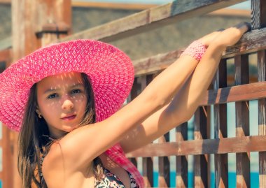 Tahta çitin yanında mayo giymiş genç bir kızın yaz portresi.