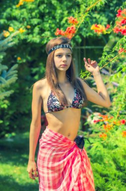 Yeşil çimlerin ve ormanın arka planında mayo giymiş manken görünümlü bir kız..