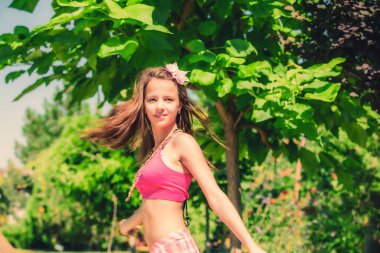 Yeşil çimenlerin ve ormanın arka planında poz veren pembe başlıklı manken görünümlü bir kız..