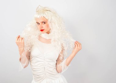 Özgüvenli ve çapkın, parlak arkaplanda tacı olan genç bir kadın.