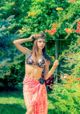 Yeşil çimlerin ve ormanın arka planında mayo giymiş manken görünümlü bir kız..