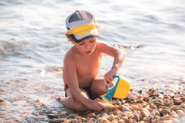 Ragazzino Una Spiaggia Ciottoli Bambino Siede Sulla Spiaggia Gioca Con — Foto Stock