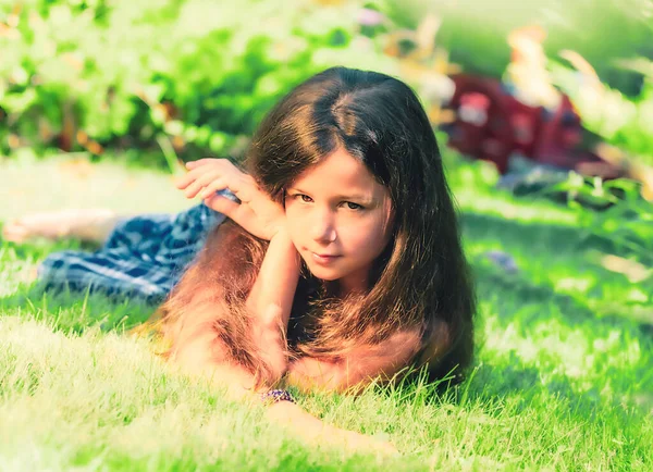 小さな女の子ブルネットでA水着敷設ダウン上の緑の草 — ストック写真