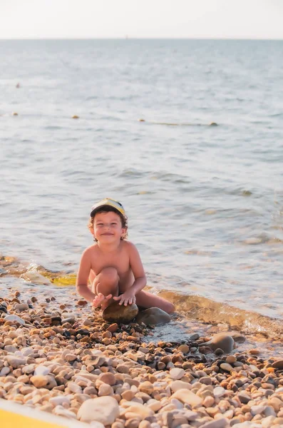 Kleine Jongen Een Kiezelstrand Een Jongetje Zit Het Strand Kijkt — Stockfoto