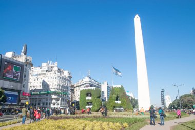 BUENOS AIRES, ARGENTINA - JULY 18, 2017: Buenos Aires sign BA covered with snow depicting the winter and Obelisk in Buenos Aires in Argentina. The Obelisk of Buenos Aires is a national historic monument and icon of Buenos Aires. clipart