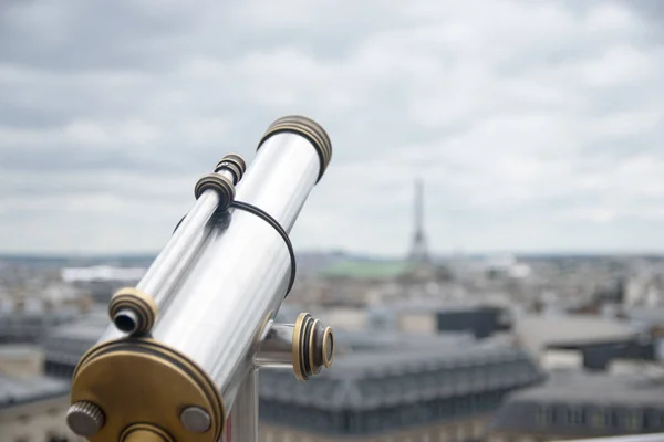 antique telescope with view over Paris, France, at dusk