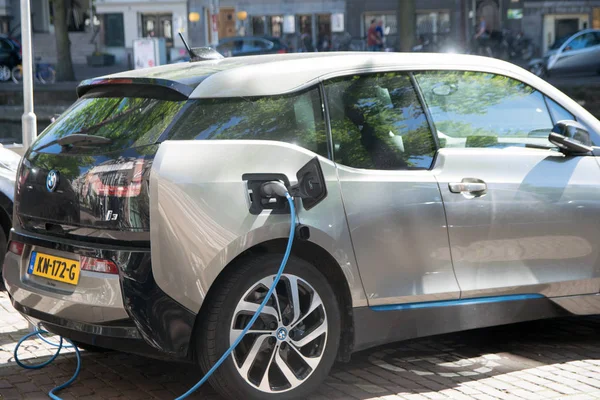 Hollanda, Amsterdam - 08 Haziran 2017: Elektrikli bir otomobil park edilmiş bir park spot şehir merkezinde bir santralde şarj ederken, görülür