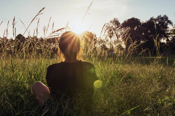 Back view of a a woman lying on wild grass at sunset