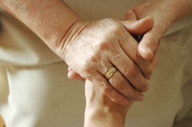 Bir aile üyesinin elini tutan yetişkin bir kadın.