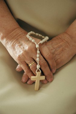 Elinde tespihle dua eden yetişkin bir kadının elleri.