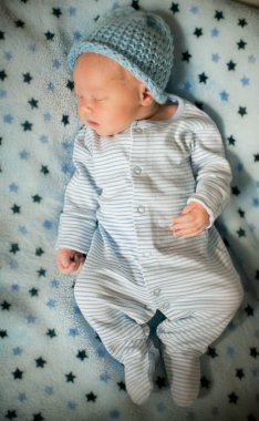 Yıldız deseni ile mavi bir battaniye üzerinde yatan yeni doğmuş bir bebek