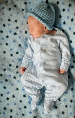 Yıldız deseni ile mavi bir battaniye üzerinde yatan yeni doğmuş bir bebek