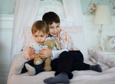 Kardeşler bir yatakta oturan birbirlerini tutarak