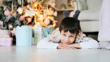 Bir Noel ağacı gülümseyen yakınındaki yalan küçük bir çocuk