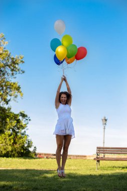 Renkli balonlar dışarıda gülümseyen süre tutan güzel genç kadın