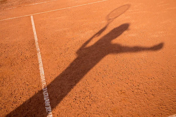 Shadow of a female tennis player serving outside