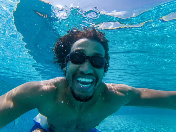 Güzel genç Afro-Amerikan adam bir selfie alarak bir yüzme havuzunda dalış