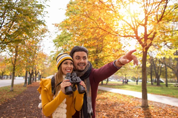 幸せな若いカップルが双眼鏡で公園で秋の散策 — ストック写真