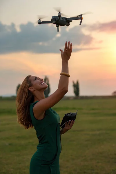 Young woman landing a drone in her hand while smiling