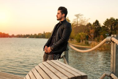 Yakışıklı genç adam yalnız nehirde gün batımını izlemek dışında ayakta