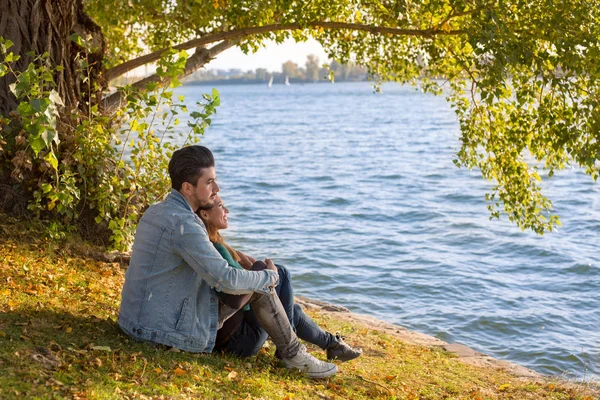 美丽愉快的情侣坐在水在秋天白天 — 图库照片