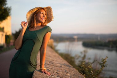 Gün batımında gülümseyen bir şapka ile güzel genç kadın dışında