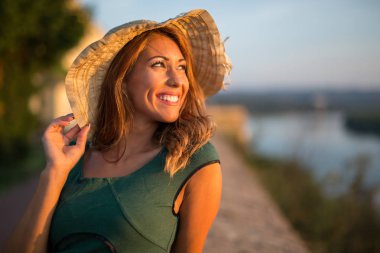 Güzel genç kadın gün batımı closeup gülümseyen bir şapka ile