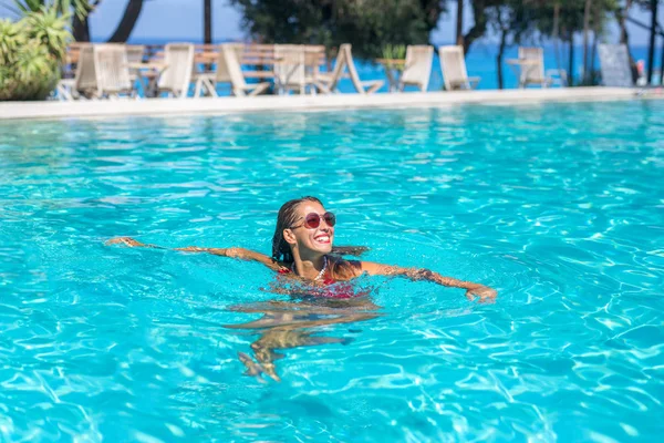 Belle jeune femme nageant dans une piscine tout en souriant — Photo