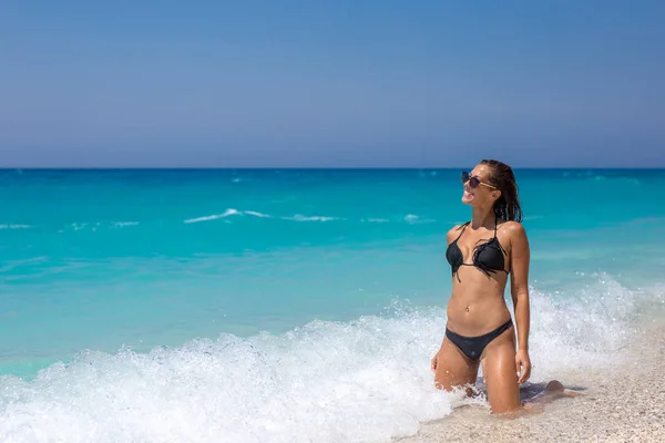 Красива молода жінка сидить на пляжі насолоджуючись хвилями — стокове фото