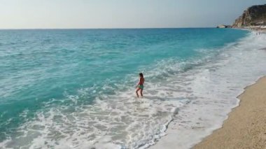 Güzel genç çocuk plajda okyanusta su oynarken