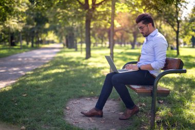 Yakışıklı genç işadamı parkta onun laptop çalışma