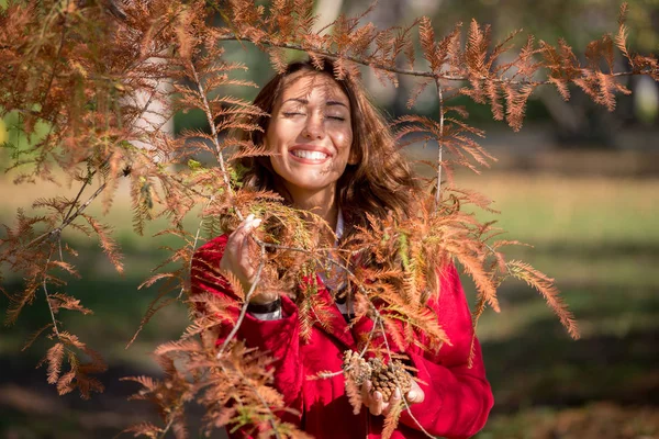 Güzel genç kadın bir sonbahar ağacının arkasında gülümsüyor — Stok fotoğraf