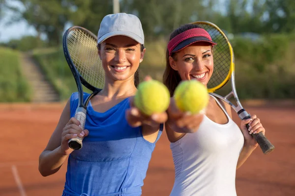 Tenis ekipmanlarını tutan iki güzel genç kadın geldi