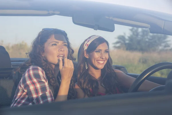 Dos chicas hermosas jóvenes conduciendo y poniendo en lápiz labial en una c — Foto de Stock
