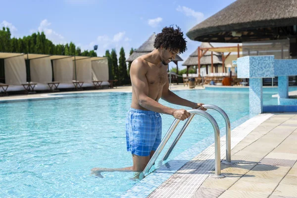 Bonito jovem afro-americano entrando em uma piscina — Fotografia de Stock