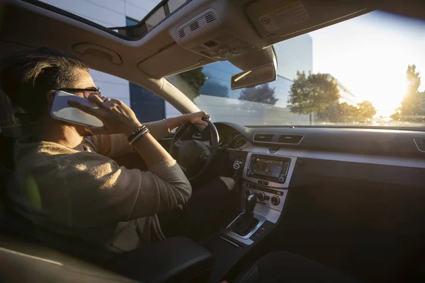Joven guapo conduciendo un coche mientras habla por teléfono — Foto de Stock