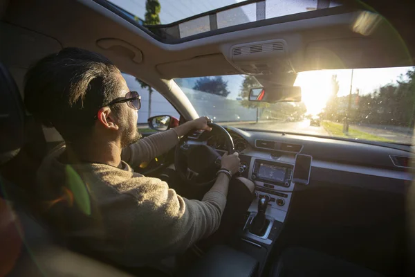 Красивий молодий чоловік за кермом своєї машини на заході сонця — стокове фото