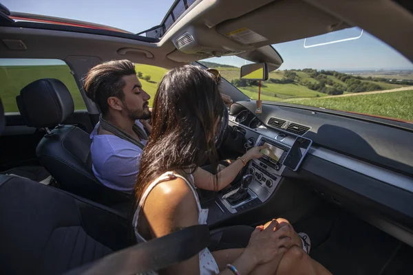 Happy young couple driving around while searching on navigation