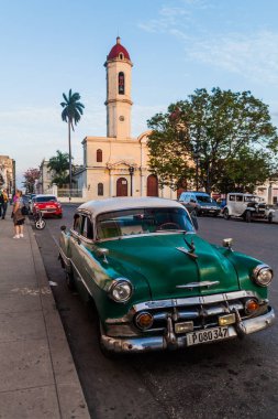 Cienfuegos, Cuba - 10 Şubat 2016: Vintage araba Parque Jose Marti Meydanı Cienfuegos, Cuba '. Catedral de la Purisima Concepcion kilise içinde belgili tanımlık geçmiş.