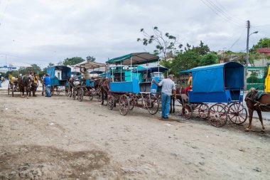 HOLGUIN, CUBA - JAN 30, 2016: Horse carriages wait for theri passengers in Holguin. clipart