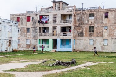 Gibara, Küba - 29 Ocak 2016: Çocuk Gibara köyünde, Küba dilipitated beton blok daireler önünde beyzbol oyun