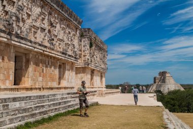 Uxmal, Meksika - 28 Şubat 2016: Turist Palacio del Gobernador (valilik Sarayı) kalıntıları antik Maya şehir Uxmal, Meksika harabelerde bina ziyaret edin. Sihirbaz içinde belgili tanımlık geçmiş piramit.