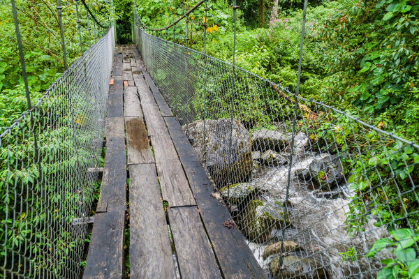 Suspension bridge at the hiking trail Sendero Los Quetzales in National Park Volcan Baru during rainy season, Panama.